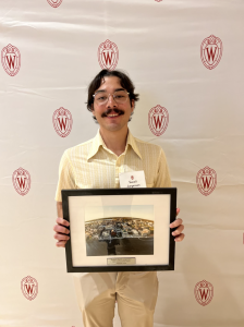 A man smiles and holds up a picture frame.